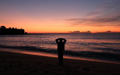 Silhouette of a person meditating at sunrise, emphasizing calmness and breathing.